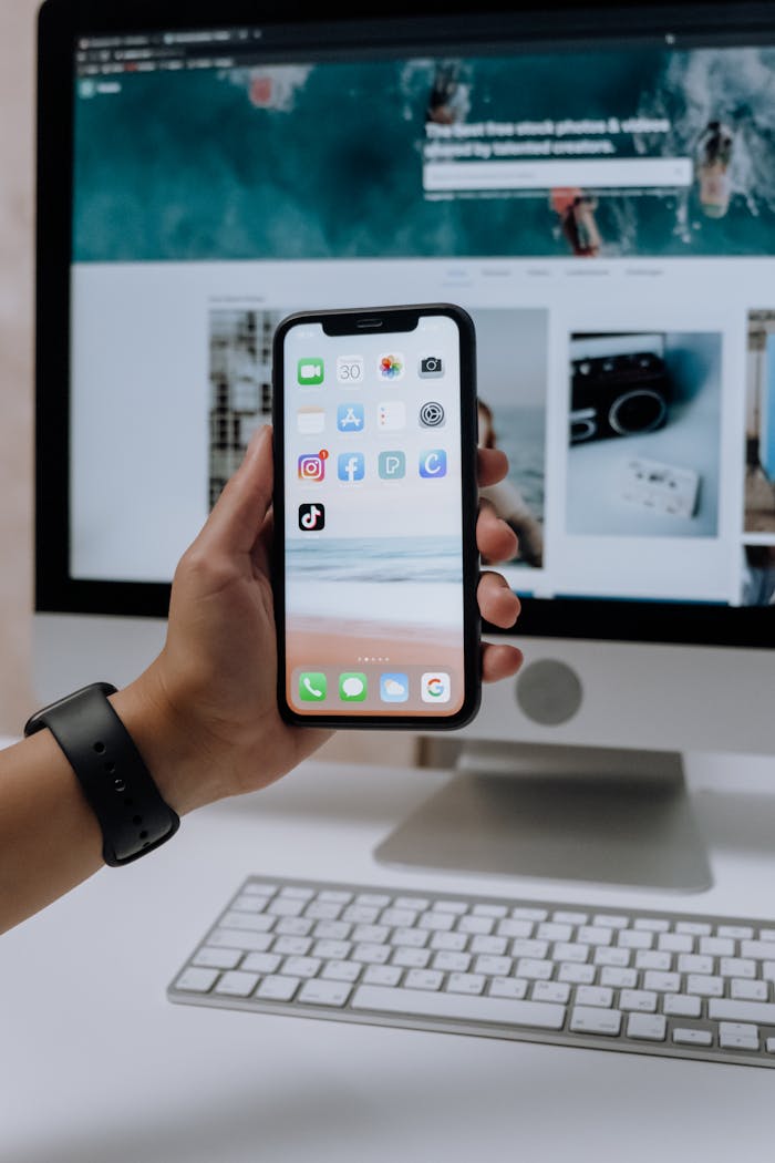 contact-img holding a smartphone in front of an imac 5082581